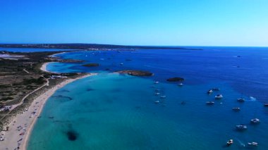 Balear Adaları 'ndaki kumlu bir sahil şeridi yakınlarında kristal berrak sularda yüzen sayısız lüks yat ve tekne. panorama genel bakış İHA 'yı indiriyor 