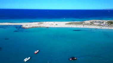 Balear Adaları 'ndaki kumlu bir sahil şeridi yakınlarında kristal berrak sularda yüzen sayısız lüks yat ve tekne. rotasyon tavası sol panorama genel görünüm drone 