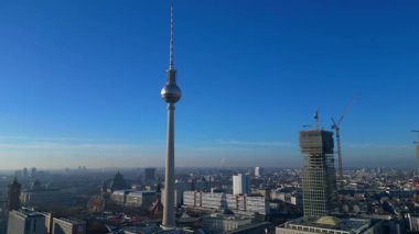 Berlins ikonik Fernsehturm 'un berrak mavi gökyüzünün altındaki şehir manzarasına hakim olduğunu gösteren hava manzarası. panorama genel görünüm dronu
