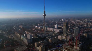 Berlins ikonik Fernsehturm 'un berrak mavi gökyüzünün altındaki şehir manzarasına hakim olduğunu gösteren hava manzarası. panorama genel bakış İHA görüntüsü yukarıdan