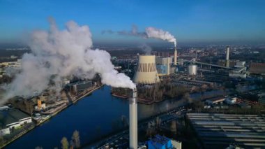 Endüstriyel ısıtma tesisinin hava görüntüsü bacası mavi gökyüzüne duman salıyor, bir kanal çevreye çarpıyor. daire görüntüsü hız rampası hiper hareket zaman aşımı