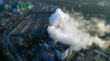Gökyüzüne duman yayan bir bacası olan sanayi kompleksi bir kanalizasyon arıtma tesisi ve kentsel altyapının yanında. Yukarıdan drone atışı
