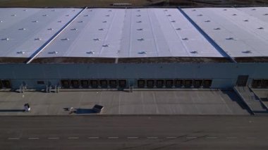Verimli lojistik ve kargo işlemleri için sayısız yükleme rıhtımı bulunan geniş bir dağıtım merkezi binasının havadan görüntüsü. Hız rampası hiper hareket zaman aşımı ters uçan İHA