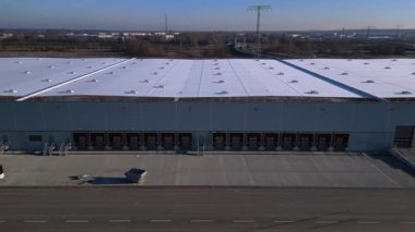 Verimli lojistik ve kargo işlemleri için sayısız yükleme rıhtımı bulunan geniş bir dağıtım merkezi binasının havadan görüntüsü. panorama genel görünüm dronu