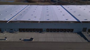 Verimli lojistik ve kargo işlemleri için sayısız yükleme rıhtımı bulunan geniş bir dağıtım merkezi binasının havadan görüntüsü. İHA panorama genel görüntüsü alçalıyor