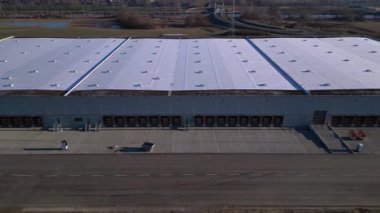 Verimli lojistik ve kargo işlemleri için sayısız yükleme rıhtımı bulunan geniş bir dağıtım merkezi binasının havadan görüntüsü. Ters İHA uçuşu