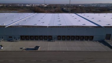 Verimli lojistik ve kargo işlemleri için sayısız yükleme rıhtımı bulunan geniş bir dağıtım merkezi binasının havadan görüntüsü. İHA yükseltiliyor