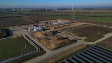 Bir güneş çiftliği ve rüzgar parkının hava görüntüsü, açık bir günde kırsal alanda sürdürülebilir enerji kaynaklarını birleştiriyor. Hız rampası hiper hareket zaman aşımı ters uçan İHA