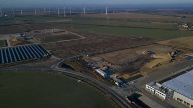 Bir güneş çiftliği ve rüzgar parkının hava görüntüsü, açık bir günde kırsal alanda sürdürülebilir enerji kaynaklarını birleştiriyor. rotasyon tavası sol panorama genel görünüm drone