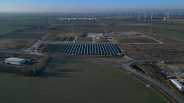 Bir güneş çiftliği ve rüzgar parkının hava görüntüsü, açık bir günde kırsal alanda sürdürülebilir enerji kaynaklarını birleştiriyor. panorama genel görünüm dronu