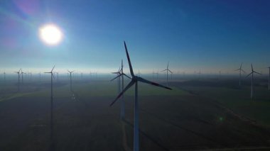 Uçsuz bucaksız kırsal bir alanda dönen rüzgar türbinleri geleceğe enerji sağlamak için temiz, sürdürülebilir ve yenilenebilir enerji sağlıyor. statik üç ayaklı insansız hava aracı