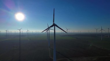 Uçsuz bucaksız kırsal bir alanda dönen rüzgar türbinleri geleceğe enerji sağlamak için temiz, sürdürülebilir ve yenilenebilir enerji sağlıyor. İHA yükseltiliyor