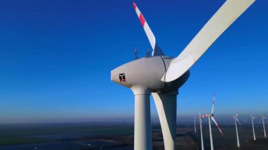 Rüzgâr türbininin kapatılması birçok türbin, güneş panelleri ve arka planda açık mavi gökyüzünün altında bir otopark ile yakın çekim. İHA yükseltiliyor