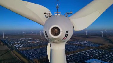 Rüzgâr türbininin kapatılması birçok türbin, güneş panelleri ve arka planda açık mavi gökyüzünün altında bir otopark ile yakın çekim. statik üç ayaklı insansız hava aracı