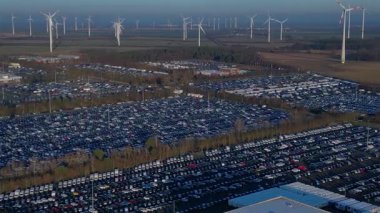 Depoları ve tren rayları olan, rüzgar türbinleriyle çevrili büyük bir dağıtım merkezinde yeni arabalar bekliyor. rotasyon pan 'dan sağ drona