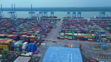 Port Klang 'ın hava görüntüsü çok sayıda renkli kargo konteynırları ve gantry vinçleri olan hareketli bir nakliye terminalini gösteriyor. rotasyon tavası sol panorama genel görünüm drone