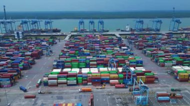 Hız rampası Klang limanının batısında çok sayıda nakliye konteynırı, kamyon ve vinç ile birlikte geniş bir konteynır görüntüsü. Drone görüntülerini daire içine al