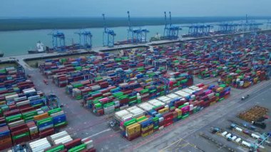 Hız rampası Klang limanının batısında çok sayıda nakliye konteynırı, kamyon ve vinç ile birlikte geniş bir konteynır görüntüsü. panorama yörünge dronu