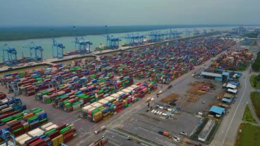 Hız rampası Klang limanının batısında çok sayıda nakliye konteynırı, kamyon ve vinç ile birlikte geniş bir konteynır görüntüsü. Uçuş üstgeçidi üzerinden uçarak ilerleyin.