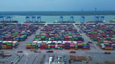 Hız rampası Klang limanının batısında çok sayıda nakliye konteynırı, kamyon ve vinç ile birlikte geniş bir konteynır görüntüsü. Takip uçuş panoraması insansız hava aracı