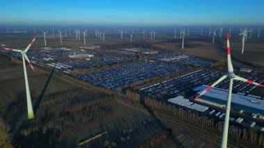 Geniş bir araba dağıtım merkezi ve araç parkına yenilenebilir enerji sağlayan büyük bir rüzgar çiftliği. Yukarıdan aşağıya drone görünümü