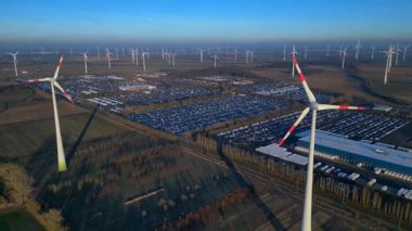 Geniş bir araba dağıtım merkezi ve araç parkına yenilenebilir enerji sağlayan büyük bir rüzgar çiftliği. Geniş yörünge panorama görünümü insansız hava aracı