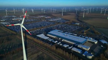 Geniş bir araba dağıtım merkezi ve araç parkına yenilenebilir enerji sağlayan büyük bir rüzgar çiftliği. Geniş yörünge panorama görünümü insansız hava aracı