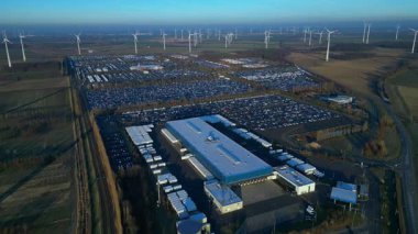 Geniş bir araba dağıtım merkezi ve araç parkına yenilenebilir enerji sağlayan büyük bir rüzgar çiftliği. Geniş yörünge panorama görünümü insansız hava aracı