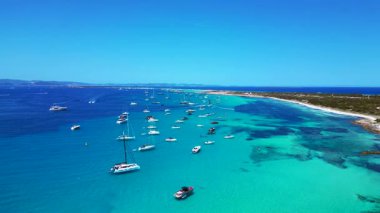 Posidonia Oceanica 'nın beyaz kumlu sahili Formentera' nın nefes kesici turkuaz sularında demirleyen tekneler. durağan tripod havada süzülen panorama drone
