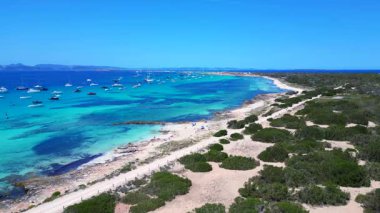 Posidonia Oceanica 'nın beyaz kumlu sahili Formentera' nın nefes kesici turkuaz sularında demirleyen tekneler. panorama genel görünüm dronu