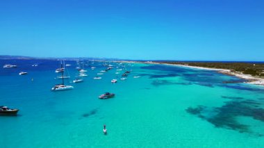 Posidonia Oceanica 'nın beyaz kumlu sahili Formentera' nın nefes kesici turkuaz sularında demirleyen tekneler. rotasyon pan 'dan sağ drona