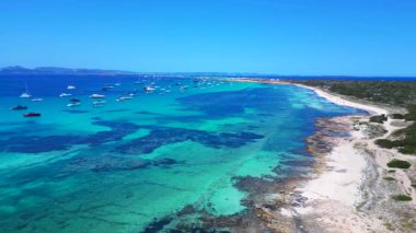 Posidonia Oceanica 'nın beyaz kumlu sahili Formentera' nın nefes kesici turkuaz sularında demirleyen tekneler. İHA 'nın üzerinden ters uçuş yap