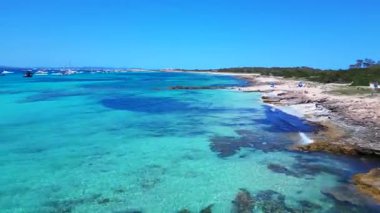 Posidonia Oceanica 'nın beyaz kumlu sahili Formentera' nın nefes kesici turkuaz sularında demirleyen tekneler. Üst uçuş panorama genel görünüm dronu
