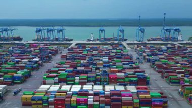 Sayısız nakliye konteynırı, kanat vinci ve kargo gemisi olan büyük bir konteynır limanının havadan görüntüsü. Ters panorama görünümü dronu uçur