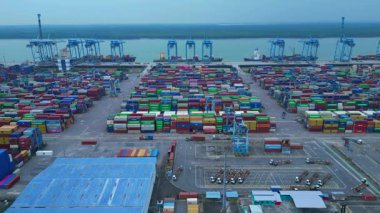 Sayısız nakliye konteynırı, kanat vinci ve kargo gemisi olan büyük bir konteynır limanının havadan görüntüsü. Dolly sol panorama genel görünüm dronu