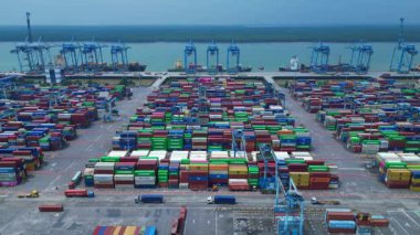 Sayısız nakliye konteynırı, kanat vinci ve kargo gemisi olan büyük bir konteynır limanının havadan görüntüsü. Yukarıdan drone atışı