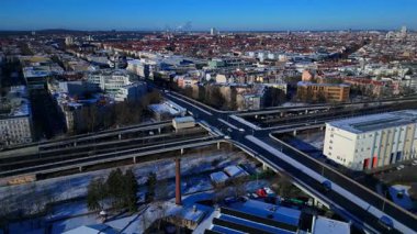 Berlin şehir manzarası, kış günlerinde karmaşık bir yol ağı, trafik akışı, demiryolu hatları ve binaları gösteriyor. Geniş yörünge panorama görünümü insansız hava aracı