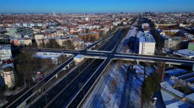 Berlin şehir manzarası, kış günlerinde karmaşık bir yol ağı, trafik akışı, demiryolu hatları ve binaları gösteriyor. Geniş yörünge panorama görünümü insansız hava aracı
