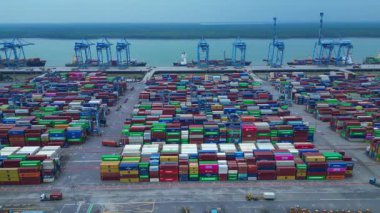 Sayısız nakliye konteynırı, kanat vinci ve kargo gemisi olan büyük bir konteynır limanının havadan görüntüsü. Dolly sol panorama genel görünüm dronu