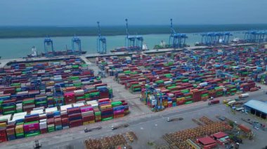 Hava görüntüsü, iskele tarafında renkli nakliye konteynırları ve büyük vinçlerle batı limanını gösteriyor. İticileri ileri çalıştır