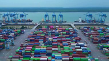 Sayısız nakliye konteynırı, kanat vinci ve kargo gemisi olan büyük bir konteynır limanının havadan görüntüsü. İHA 'nın üzerinden ters uçuş yap