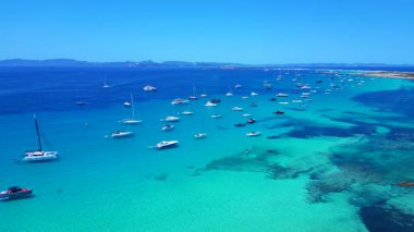 Formentera Balearic Adası 'nın berrak turkuaz sularına demirlenmiş pek çok zevk teknesinin hız rampası hızlandırılmış hareket süresi. İHA panorama genel görüntüsü alçalıyor