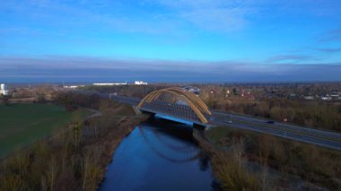 Modern Alman otoyol köprüsünün hız rampası nehir üzerinde araç trafiğini taşıyor ve peyzajları birbirine bağlıyor. İticileri ileri çalıştır