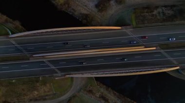 Modern Alman otoyol köprüsünün hız rampası nehir üzerinde araç trafiğini taşıyor ve peyzajları birbirine bağlıyor. İHA kamerası aşağı dönerek sağa döndür