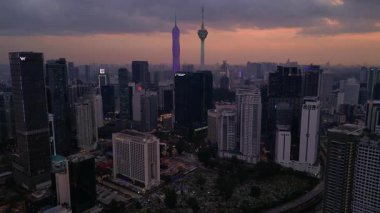 Kuala Lumpur şehri, kentsel gelişimi temsil eden aydınlık Merdeka 118 gökdeleni ve KL Kulesi 'nin yer aldığı güzel bir günbatımında ufuk çizgisine sahiptir. İticileri ileri çalıştır