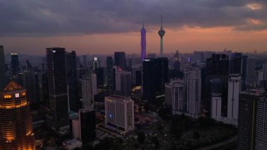 Kuala Lumpur şehri, kentsel gelişimi temsil eden aydınlık Merdeka 118 gökdeleni ve KL Kulesi 'nin yer aldığı güzel bir günbatımında ufuk çizgisine sahiptir. rotasyon tavası sol drona