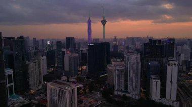 Kuala Lumpur şehri, kentsel gelişimi temsil eden aydınlık Merdeka 118 gökdeleni ve KL Kulesi 'nin yer aldığı güzel bir günbatımında ufuk çizgisine sahiptir. Ters İHA uçuşu