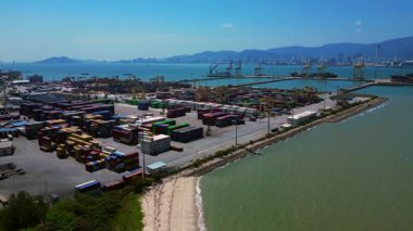 Penang Limanı 'nın Kuzey Butterworth Terminali' nin kıyı şeridi boyunca sayısız nakliye konteynırı, vinç ve gemileriyle hava görüntüsü. statik panorama havada süzülen drone
