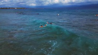Gençler, açık ve sığ tropikal denizde sörf tahtası becerileri öğrenip pratik yapıyorlar. Yukarıdaki İHA 'dan izlenen çekim