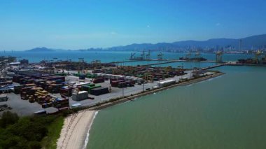 Penang Limanı 'nın Kuzey Butterworth Terminali' nin kıyı şeridi boyunca sayısız nakliye konteynırı, vinç ve gemileriyle hava görüntüsü. İticileri ileri çalıştır